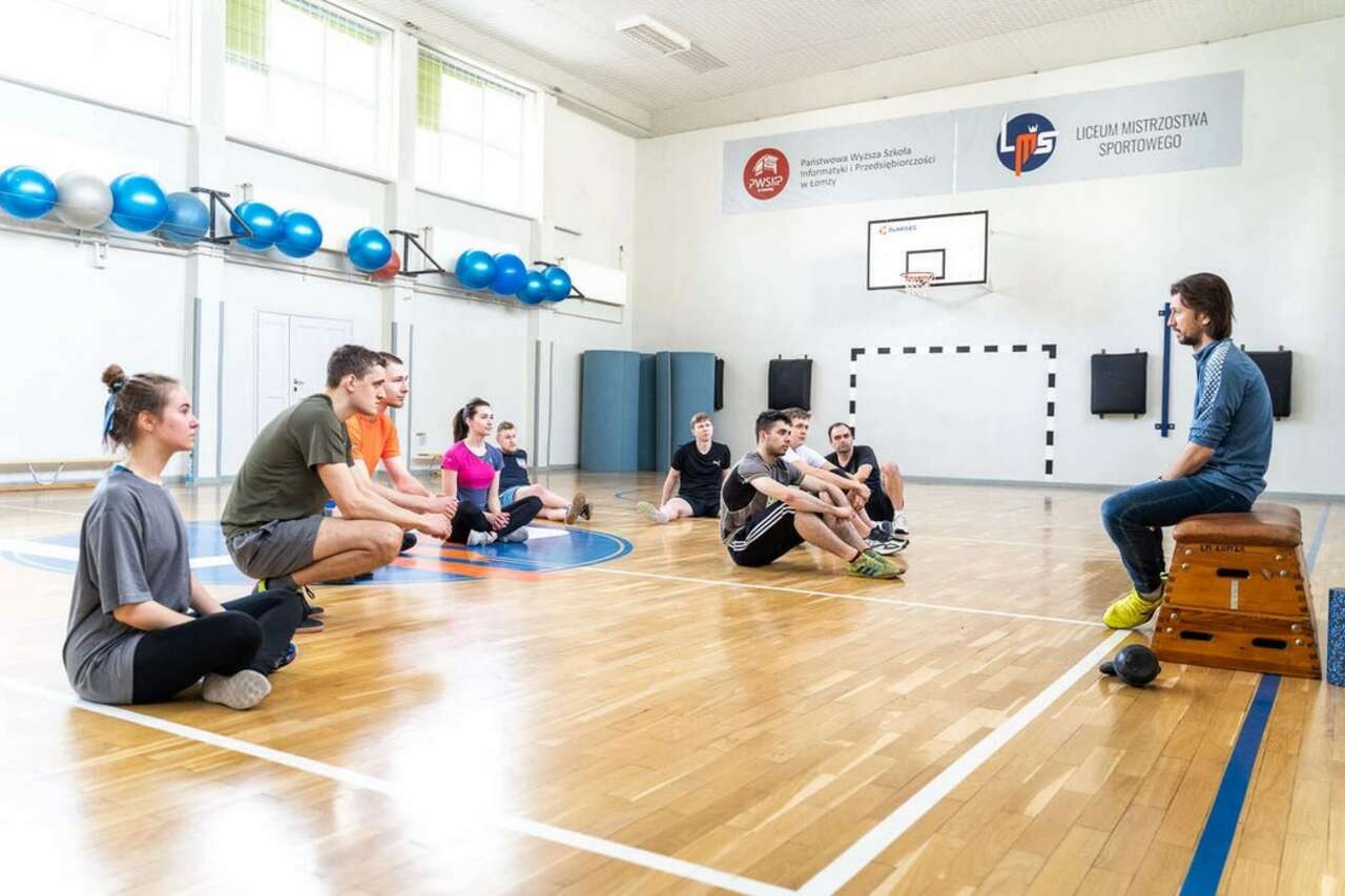 zdjęcie przedstawia grupę młodych ludzi na sali gimnastycznej