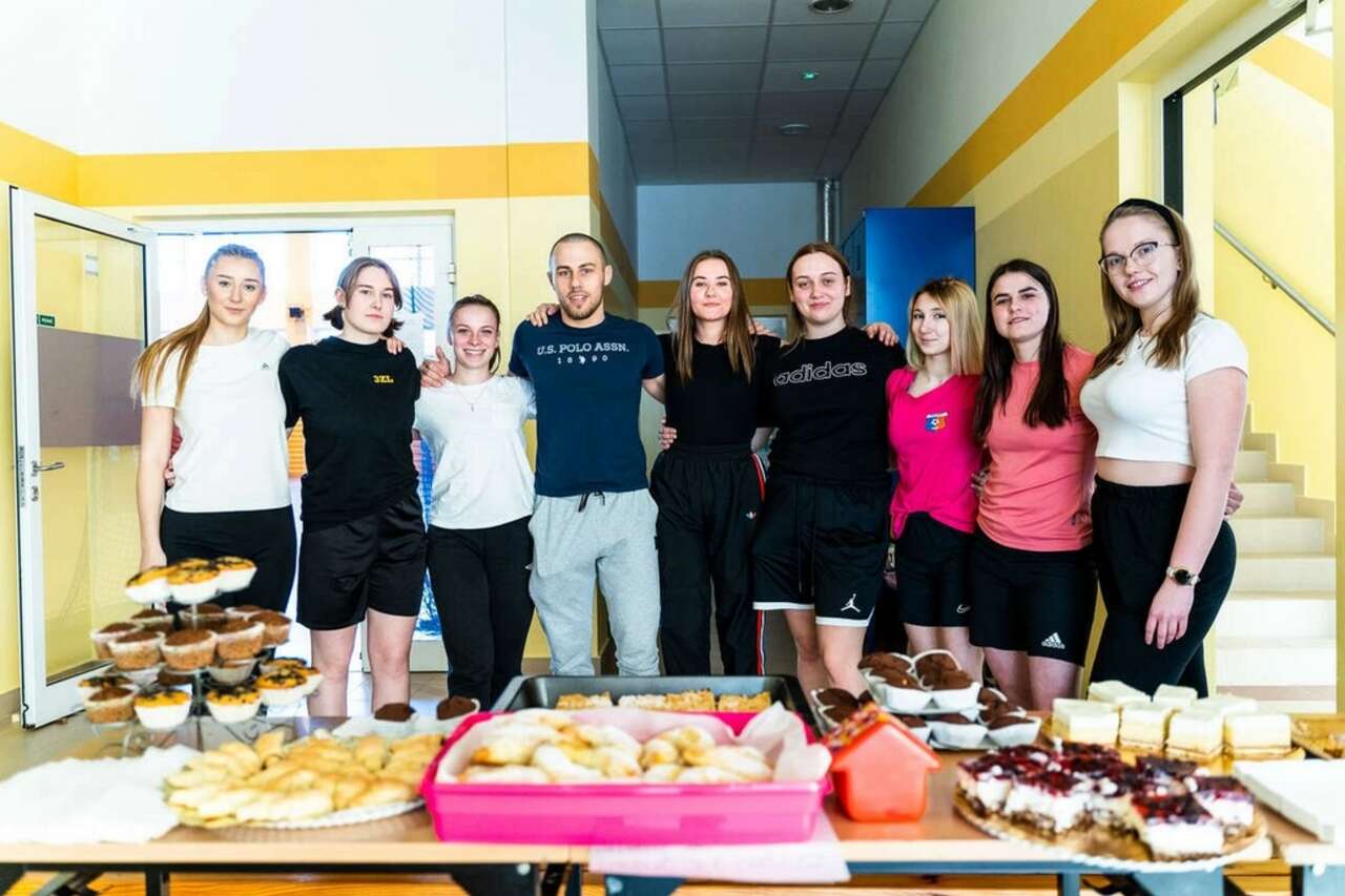 zdjęcie przedstawia grupę studentów i stół ze słodkościami